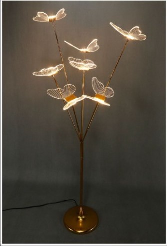 Elegant LED floor lamp with golden base and acrylic butterfly-shaped lights on delicate stems, glowing in warm white light against a grey background